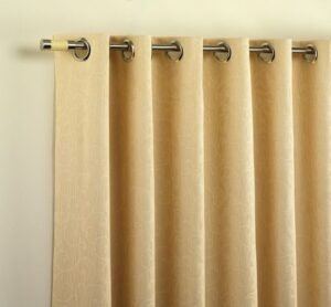 Cream eyelet curtains hanging in folds from a metal pole