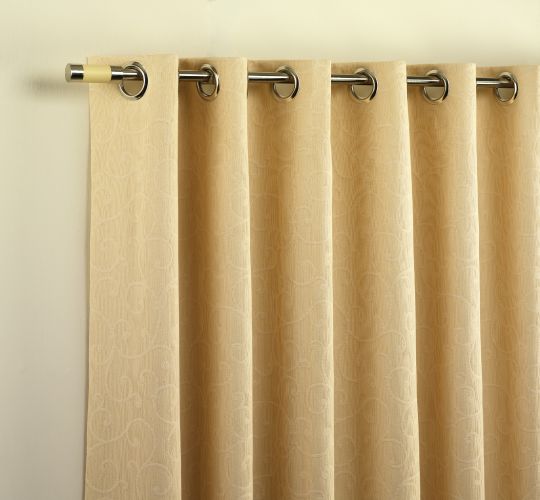 Cream eyelet curtains hanging in folds from a metal pole